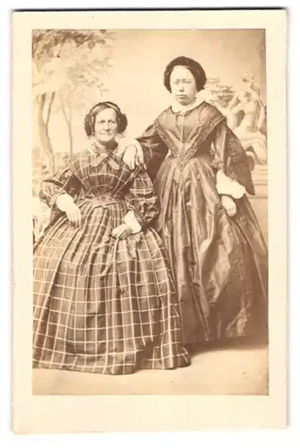 Fotografie Heinrich Fritz, Greiz, Portrait zwei ältere Damen in Biedermeierkleidern vor einer Studikulisse