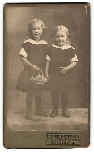 Fotografie Heinrich Petersen, Schleswig, Stadtweg 34, Portrait zwei kleine Mädchen in Kleidern mit Blumenkorb