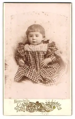 Fotografie Curt Born, Kamenz i. S., Ost-Strasse, Drolliges Mädchen mit Knopfaugen in kariertem Kleid