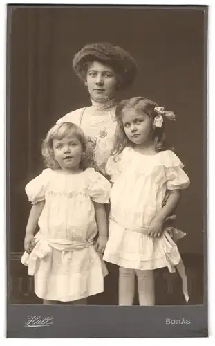 Fotografie Hall, Boras, Portrait Mutter mit zwei niedlichen Töchtern in weissen Kleidern, Mutterglück