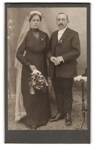 Fotografie unbekannter Fotograf und Ort, Portrait Eheleute im schwarzen Hochzeitskleid und Anzug