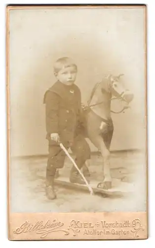 Fotografie Billström, Kiel, Vorstadt 9, Portrait kleiner Knabe mit grossen Schaukelpferd und Gerte