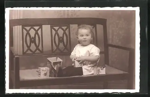 Foto-AK Kleinkind auf Bank mit Spielklötzen, Spielzeug, 1933