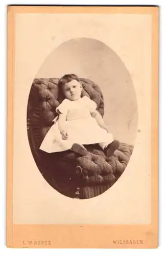 Fotografie L. W. Kurtz, Wiesbaden, Kleinkind in weissem Kleid auf Sessel