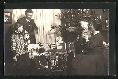 Foto-AK Familie beim Weihnachtsfest, Mädchen bekommt Puppe geschenkt