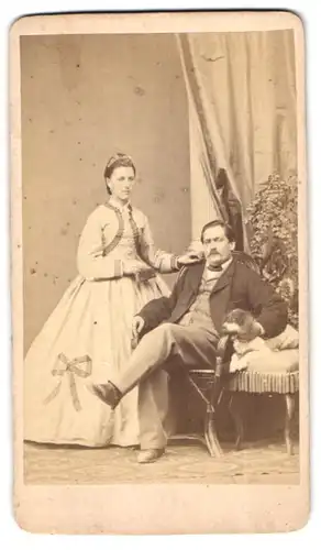 Fotografie unbekannter Fotograf und Ort, Portrait vornehmens Paar im Biedermeierkleid mit Ihrem Hund im Atelier