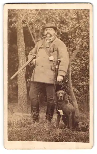 Fotografie W. Ohm, Braunschweig, Portrait Jäger mit seinem Jagdhund im Wald, Flinte, Hirschfänger, Pfeife