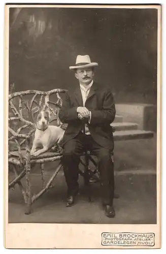 Fotografie Emil Brockhaus, Gardelegen, Portrait Mann im Anzug mit Hut und seinem Terrier im Atelier