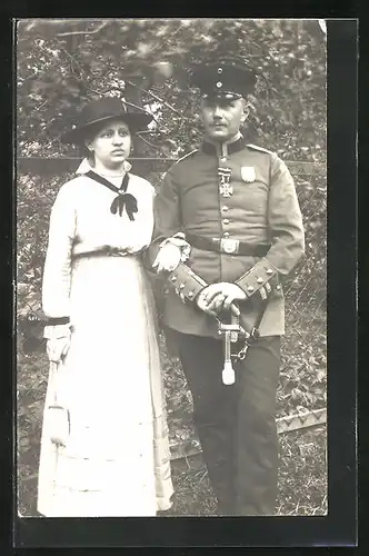 Foto-AK Soldat in Uniform mit Schirmmütze und Eisernem Kreuz neben Frau, Uniformfoto