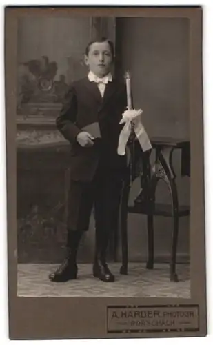 Fotografie A. Harder, Rorschach, Portrait junger Knabe im Anzug mit Kommunionskerze