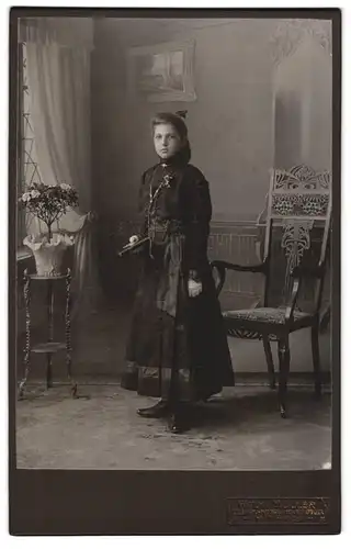Fotografie Wilhelm Müller, Hof a. S., Portrait junge Frau im schwarzen Kleid mit Bibel zur Kommunion, Studiokulisse