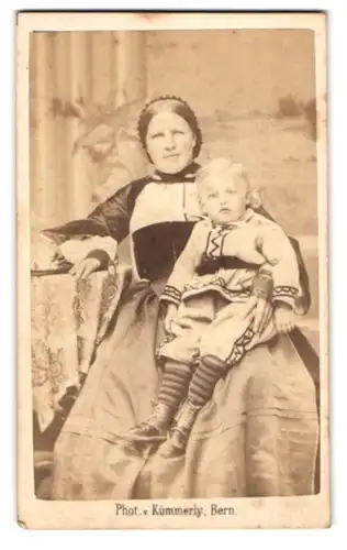 Fotografie Kümmerly, Bern, Schweizer Dame in Tracht mit Kleinkind auf dem Schoss