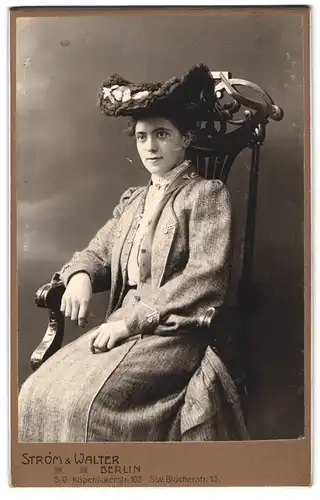 Fotografie Strom & Walter, Berlin, Köpenickerstr. 102, junge brünette Dame mit modischem Hut auf Sessel sitzend