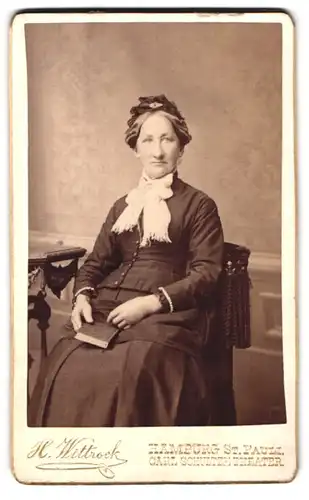 Fotografie H. Wittrock, Hamburg, Portrait ältere DAme im dunklen Kleid mit Schleife und Haarschmuck