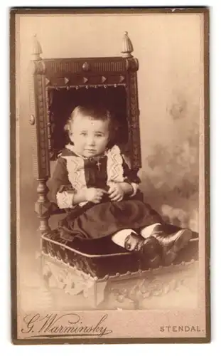 Fotografie G. Warminsky, Stendal, Portrait kleines Mädchen im Kleidchen mit Kruzifix auf einem samt Stuhl