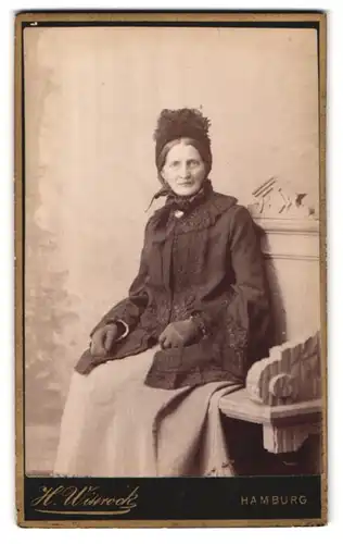 Fotografie H. Wittrock, Hamburg, Portrait ältere Dame im schlichten Kleid mit Haube udn Handschuhen