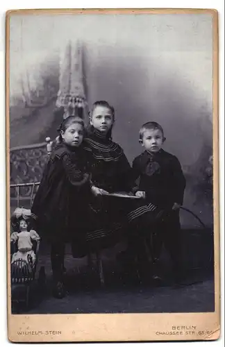 Fotografie Wilhelm Stein, Berlin, Portrait zwei Schwestern mit Bruder und Puppe im Atelier