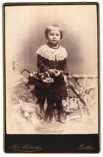 Fotografie B. Münchs, Gotha, Portrait niedliches Mädchen mit Topfhaarschnit im Samtkleid mit Körbchen