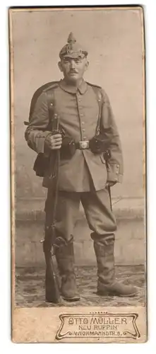 Fotografie Otto Müller, Neu Ruppin, Portrait Soldat Carl Gaechike in Feldgrau Rgt. 19, Pickelhaube Tarnbezug, Karabiner