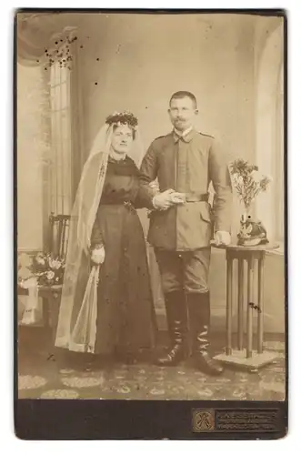 Fotografie A. Kiesewalter, Marklissa a. Qu., Portrait Soldat in Feldgrau Uniform mit preussischen Tschako, Kriegshochzeit