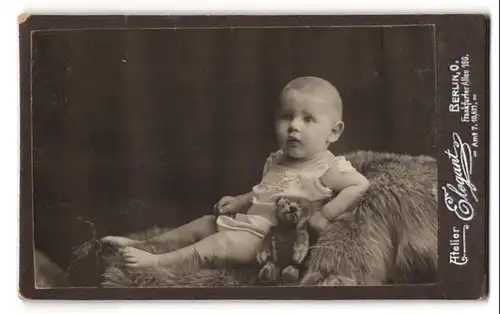 Fotografie Atelier Elegant, Berlin, Frankfurter Allee 160, Baby mit Teddybär auf Felldecke liegend