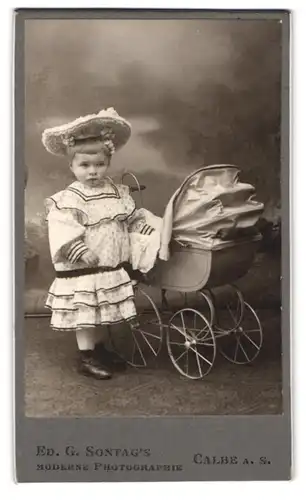 Fotografie Ed. G. Sontag, Calbe / Saale, niedliches Mädchen im Sonnntagskleid mit Hut & Puppenwagen