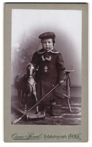 Fotografie Oscar Spoerl, Gera, Schleizer Strasse 34, Knabe im Matrosenazug mit Spielzeug-Pferd & Reitgerte