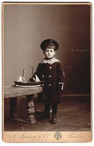 Fotografie A. Jandorf & Co., Berlin, Kottbuserdamm 1-2, Knabe in Marineuniform mit Schiffsmodell