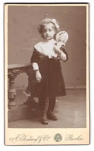Fotografie A. Jandorf & Co., Berlin-S., Kottbusserdamm 1-2, Portrait kleines Mädche im Kleid mit Puppe