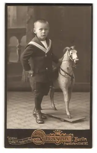 Fotografie Adolf Haynn, Berlin, Frankfurter Allee 197, Knabe im Matrosenanzug nebst Spielzeugpferd