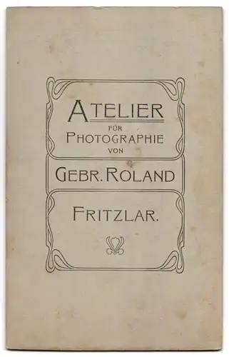 Fotografie Gebrüder Roland, Fritzlar, mürrisch blickendes Mädchen mit Ball im Puppenwagen