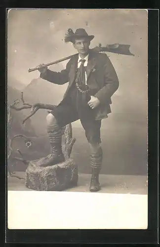 Foto-AK Jäger in Tracht mit Gewehr vor Gebirgslandschaft, Studiokulisse