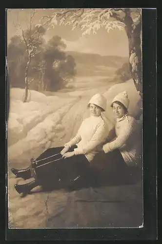 AK zwei Frauen sitzen auf einem Schlitten vor einer Winterlandschaft