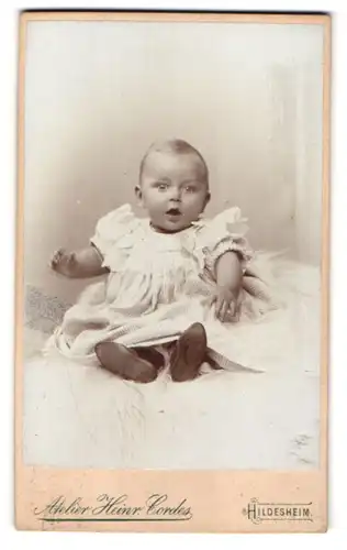 Fotografie Heinr. Cordes, Hildesheim, Zingel 36, Portrait lebhaftes Baby im Hemdchen