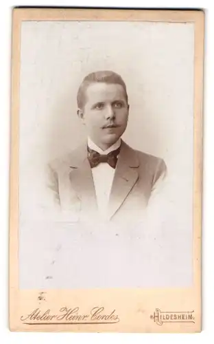 Fotografie Heinr. Cordes, Hildesheim, Zingel 36, Portrait eleganter junger Herr mit Fliege