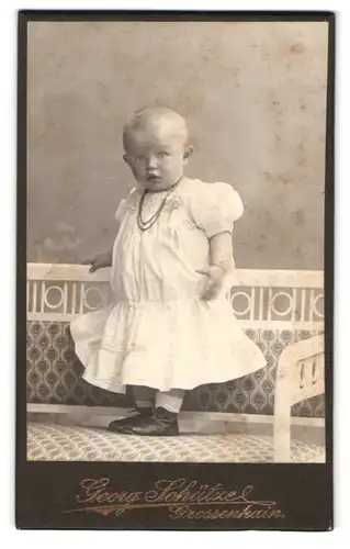 Fotografie Georg Schütze, Grossenhain, Portrait niedliches Kleinkind im weissen Kleidchen