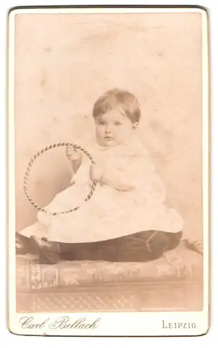 Fotografie Carl Bellach, Leipzig, Gellertstr. 12 u. 14, Portrait niedliches Baby mit Spielreifen in der Hand