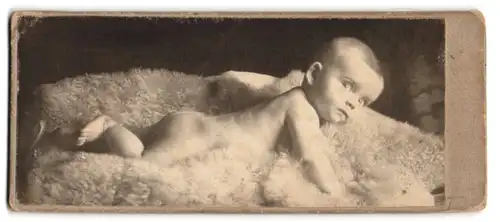 Fotografie unbekannter Fotograf und Ort, niedliches Baby liegend auf einem Fell