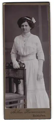 Fotografie Arthur Heinemann, Hainichen, Portrait hübsche Dame im weissen Spitzenkleid und Haarschleife