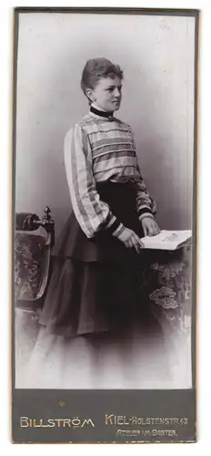 Fotografie Billström, Kiel, Holstenstr. 43, Portrait junge Frau mit Buch und modisch getreifter Bluse