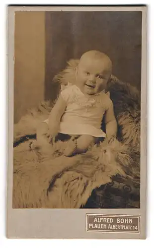 Fotografie Alfred Bohn, Plauen, Albertplatz 14, Portrait entzückendes lachendes Baby auf einem Fell