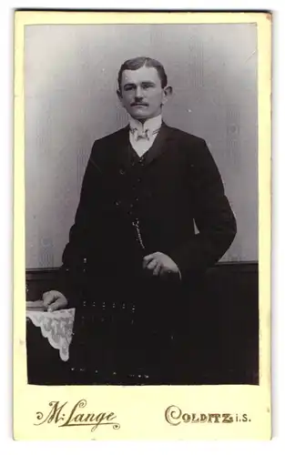 Fotografie M. Lange, Colditz i. S., Fürstenweg, Portrait eleganter Herr vor einer Wand mit Tapete