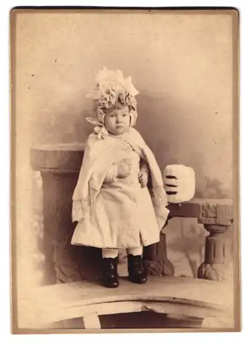 Fotografie kleines Mädchen trägt Mantel & Haube, Muff auf Brüstung liegend