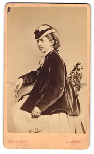 Fotografie Gebr. Martin, Augsburg, Portrait junge Frau im weissen Kleid mit Samtjacke und Hut