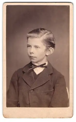 Fotografie Ferd. Grosser, Bernstadt i. Schl., Portrait junger blonder Knabe im dunklen karierten Anzug mit Seitenscheitel