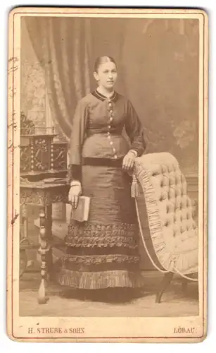 Fotografie H. Strube & Sohn, Löbau i. S., Bumenstrasse 339, Portrait junge Dame im zeitgenössischen Kleid mit Buch