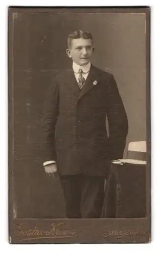 Fotografie Gustav Krenz, Schirgiswalde, Portrait eleganter junger Mann im Anzug mit Ansteckblume