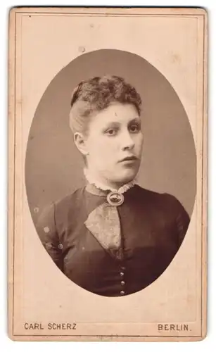 Fotografie Carl Scherz, Berlin, Holzmarktstr. 71, Portrait ernste junge Dame mit Haardutt und Brosche