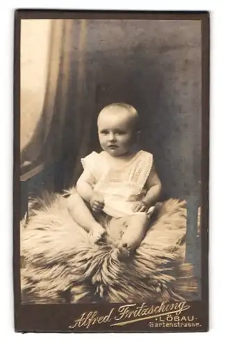 Fotografie Alfred Fritzsching, Löbau, Gartenstrasse, Portrait niedliches Baby auf einem Fell