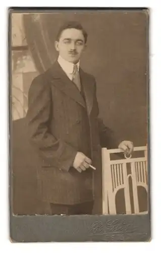 Fotografie R. Glöss, Gersdorf, Portrait eleganter Herr im Anzug mit Krawatte und Zigarette